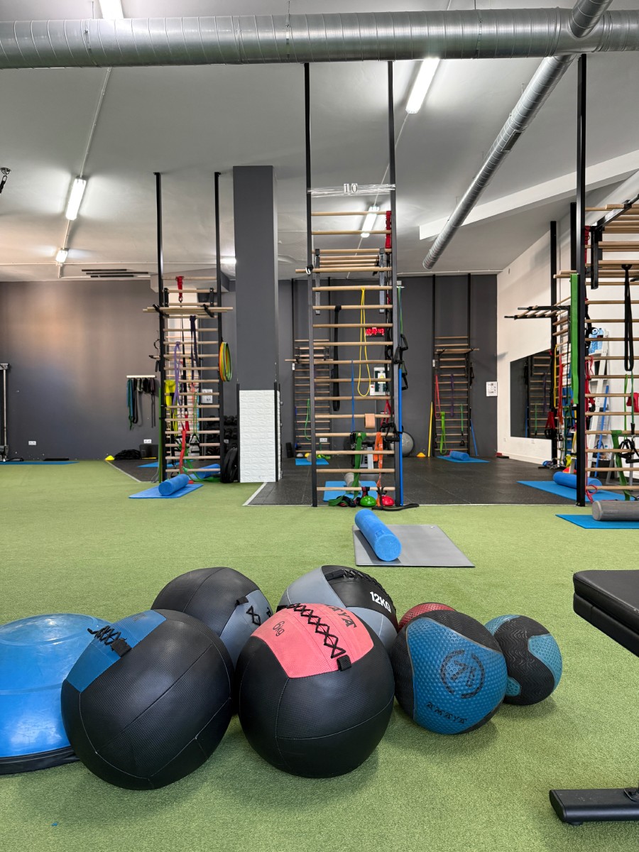 Balones medicinales en el suelo de un gimnasio con estructuras de entrenamiento - Saludx10