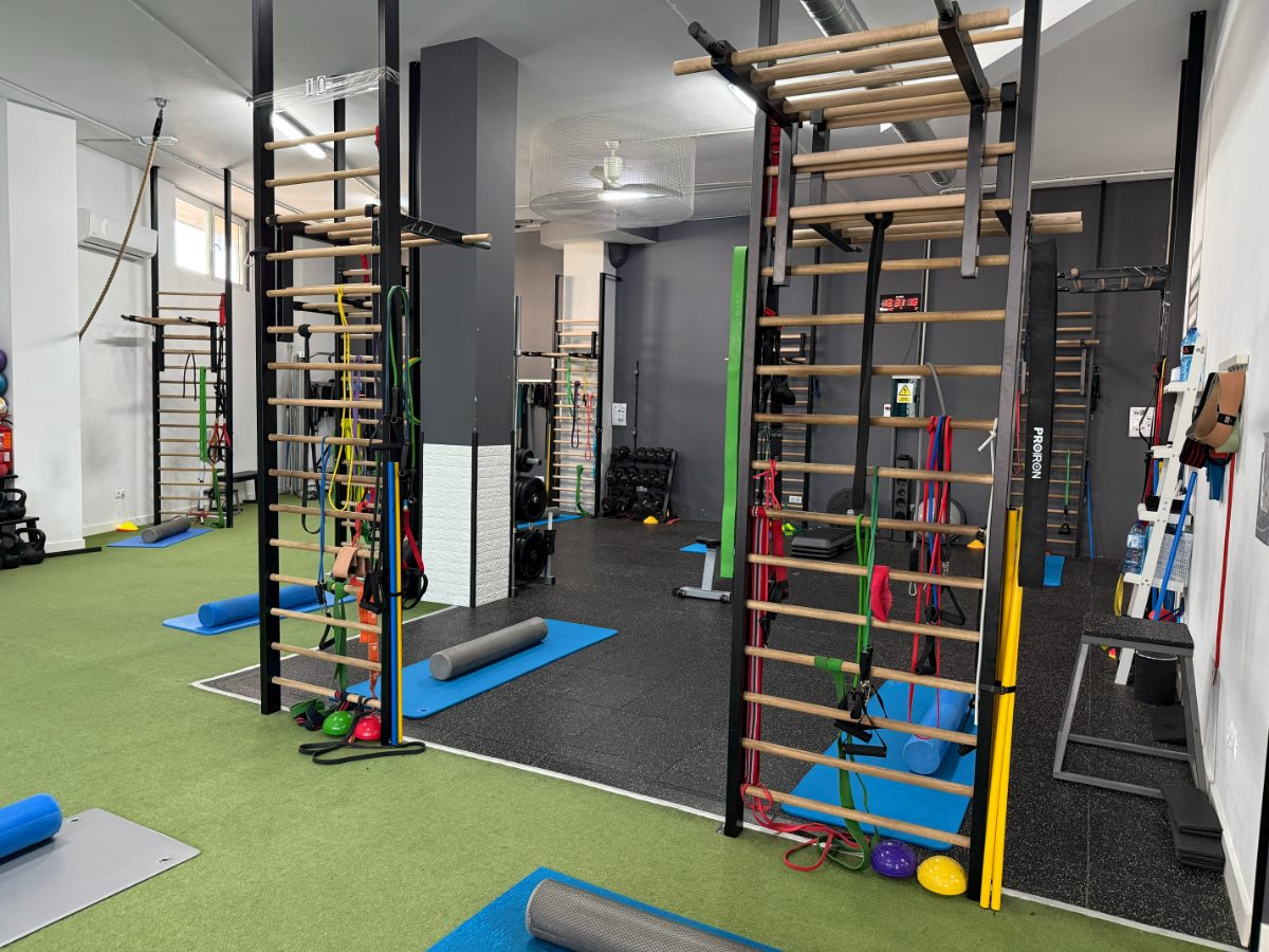 Interior de gimnasio con espalderas, bandas elásticas y colchonetas de ejercicio - Saludx10