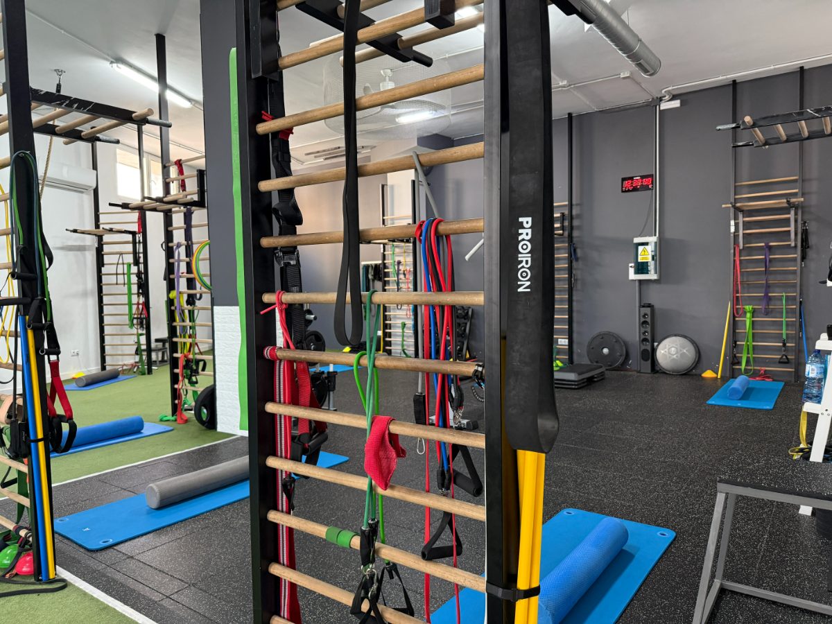 Interior de gimnasio con espalderas, bandas elásticas y colchonetas para entrenamiento personalizado - Saludx10